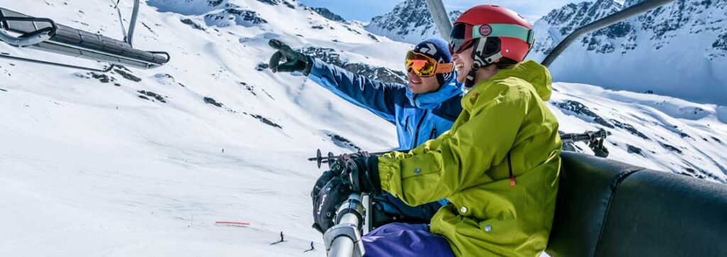 Two friends on a chairlift laughing