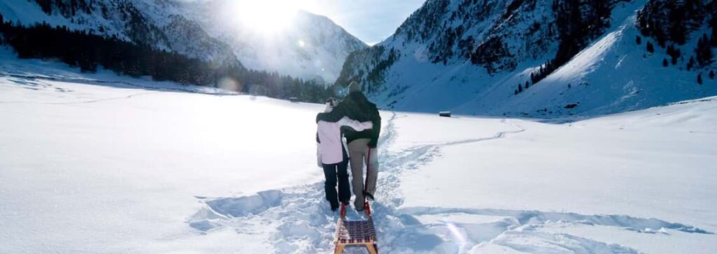 A father and daughter dragging a toboggan through the snow