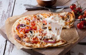 A cheesy pizza slice being served at the restaurant Chez Paulo in Val d'Isere